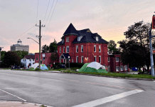 Simcoe takes over downtown Busby Centre properties A photo of a red brick building, which is known as the Busby Centre, with tents set up on the surrounding lawn.